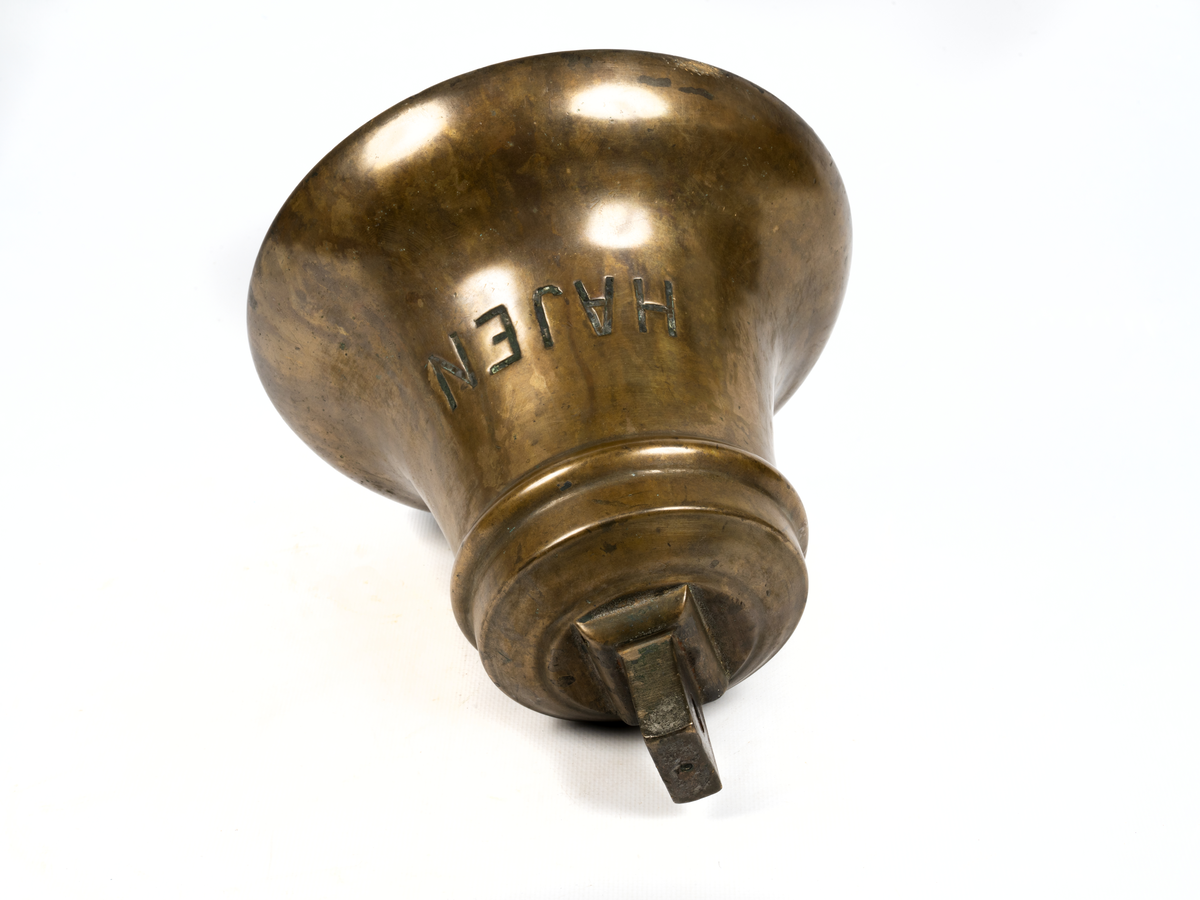 Skeppsklocka av malm, grönmålad med kläpp av järn.