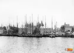 Vedskutor och pråmar vid kaj någonstans i Stockholm. Det är 