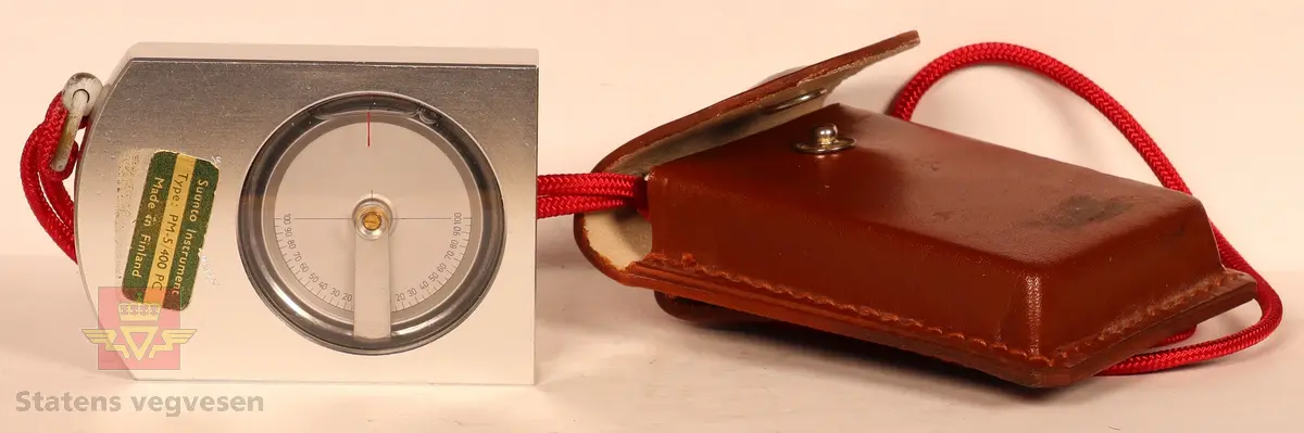 Måleinstrument i "lommestørrelse" med tilhørende veske/etui i skinn, samt bruksanvisning på papir. Måleinstrumentet i metall har nivell og gradmåler skalert fra 0-100.