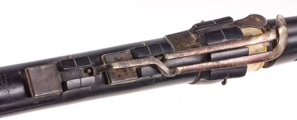 Tvärflöjt i mörkt trä med ringar av elfenben. 5 delar. Sprickor i munstycke, päron, undre mellandelen och ringen mellan mellanstyckena. Den senare är lagad med en metallring satt runt originalringen. Konisk form. 7 klaffar med kvadratisk platta och bocklagring.