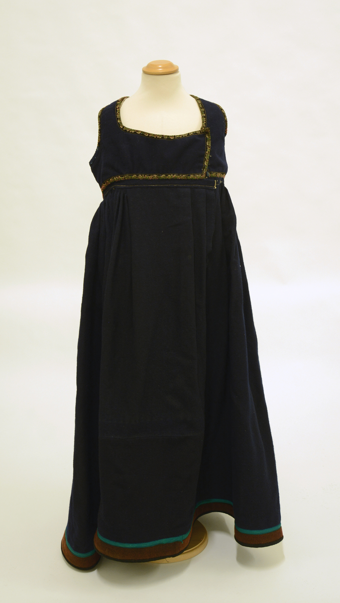 Drakt som består av
 A) overdel,
 B) stakk,
 C) trøye og
 D) forkle. 
Opplysninger fra protokollen: 
b) Stakk av blaatt vadmaal, skoren i 5 breiddir, smaarykt, med stiv kanting og skoning nede, borda ei brun vadmaalsstrime med grønt skillingsband. Til stakken høyrer heimevovne, brogda selar. ( Sekundært påsydd skoning med svart vadmel)
c) Trøye av blaatt vadmaal kanta med grøne og svartmynstra fløyelsborder (paa ermane svart fløyelskant). Trøyeblokune er skorne paa lag som uppluten, hev ei smal rispe nede bak, med 2 lask, og er til aa hekte framme. Dei tviblokka ermane hev litt rykkjing ved herdi og smaa stigle paa ermi framme. Sidd bak ikr. 29 cm
d) Bomullsfyrklæde med brogda fyrklædebunad, fyriklædet er graabrunt med strimur av svarte rankur fyldte med ljosare triblad. Sidd ikr. 1 m.