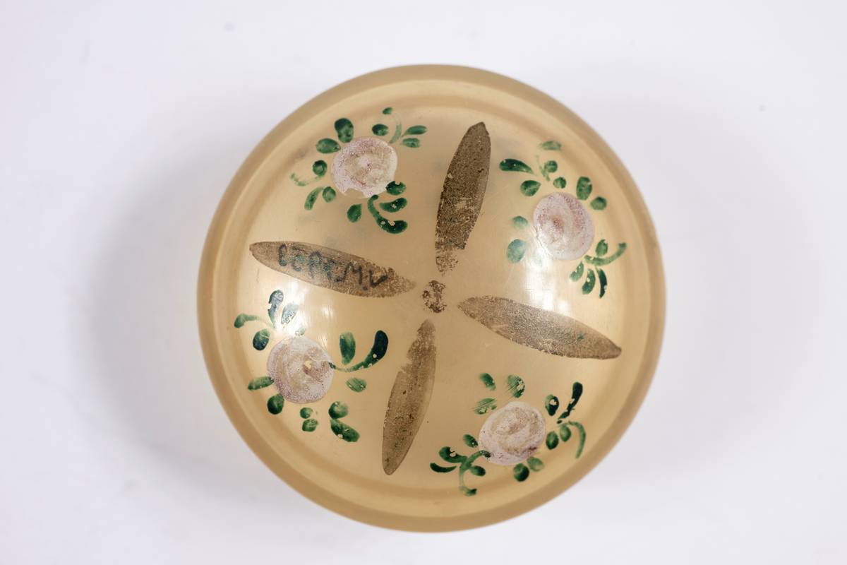 Svarvad av horn (tunnt som celluloid), med kupigt lock och botten. På locket målade rosor.