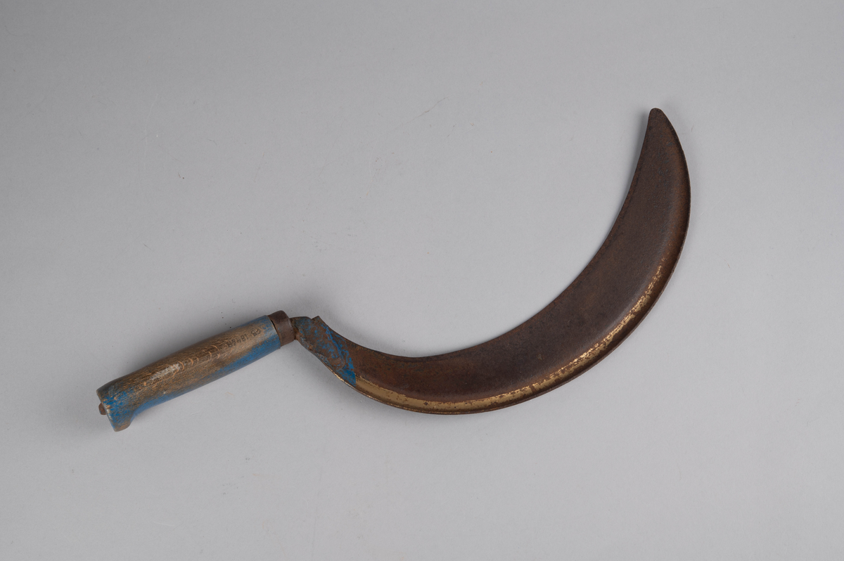 Form: rett åpen sigdform. Håndtak med håndstøtte i enden, og liten jernholk øverst. Bladets 'hale' går gjennom hele håndtaket og 'låses' i enden av dette. Rester av blåmaling på håndtak og gullbronse-stafferingen på bladet