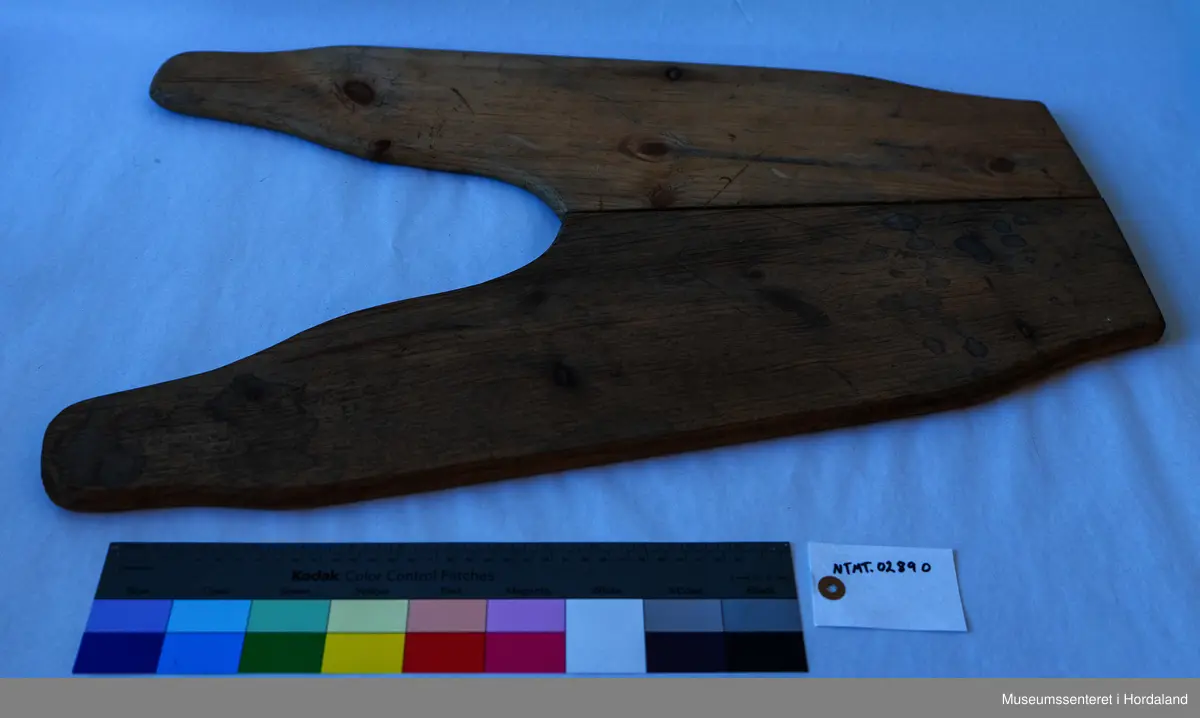 Bukseformer i tre. Kan brettes i to, Ble antakeligvis brukt til å tørke og forme ferdige underbukser før salg. Den har to hengsler.