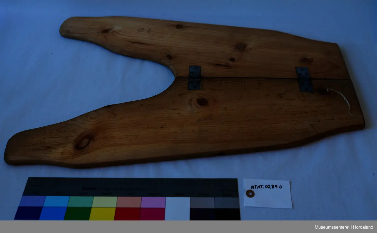 Bukseformer i tre. Kan brettes i to, Ble antakeligvis brukt til å tørke og forme ferdige underbukser før salg. Den har to hengsler.