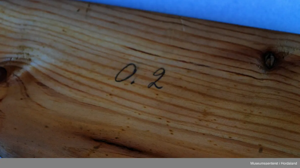 Bukseformer i tre. Kan brettes i to, Ble antakeligvis brukt til å tørke og forme ferdige underbukser før salg. Den har to hengsler.