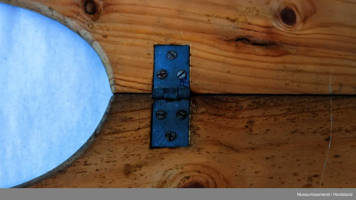 Bukseformer i tre. Kan brettes i to, Ble antakeligvis brukt til å tørke og forme ferdige underbukser før salg. Den har to hengsler.