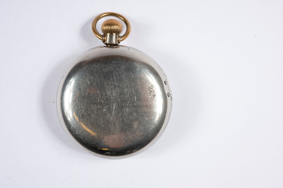 Herrmodell med förnicklat fodral. Boetten i silver och guld. Rikt graverat på baksidan. Stämplad DMF o CO på insidan locket och innanför Cylindre o Rubis. Urtavlan har romerska siffror, minutsiffror vid varje 5 minuter i arabiska siffror. Separat sekundvisare nertill. Kron uppdragning.