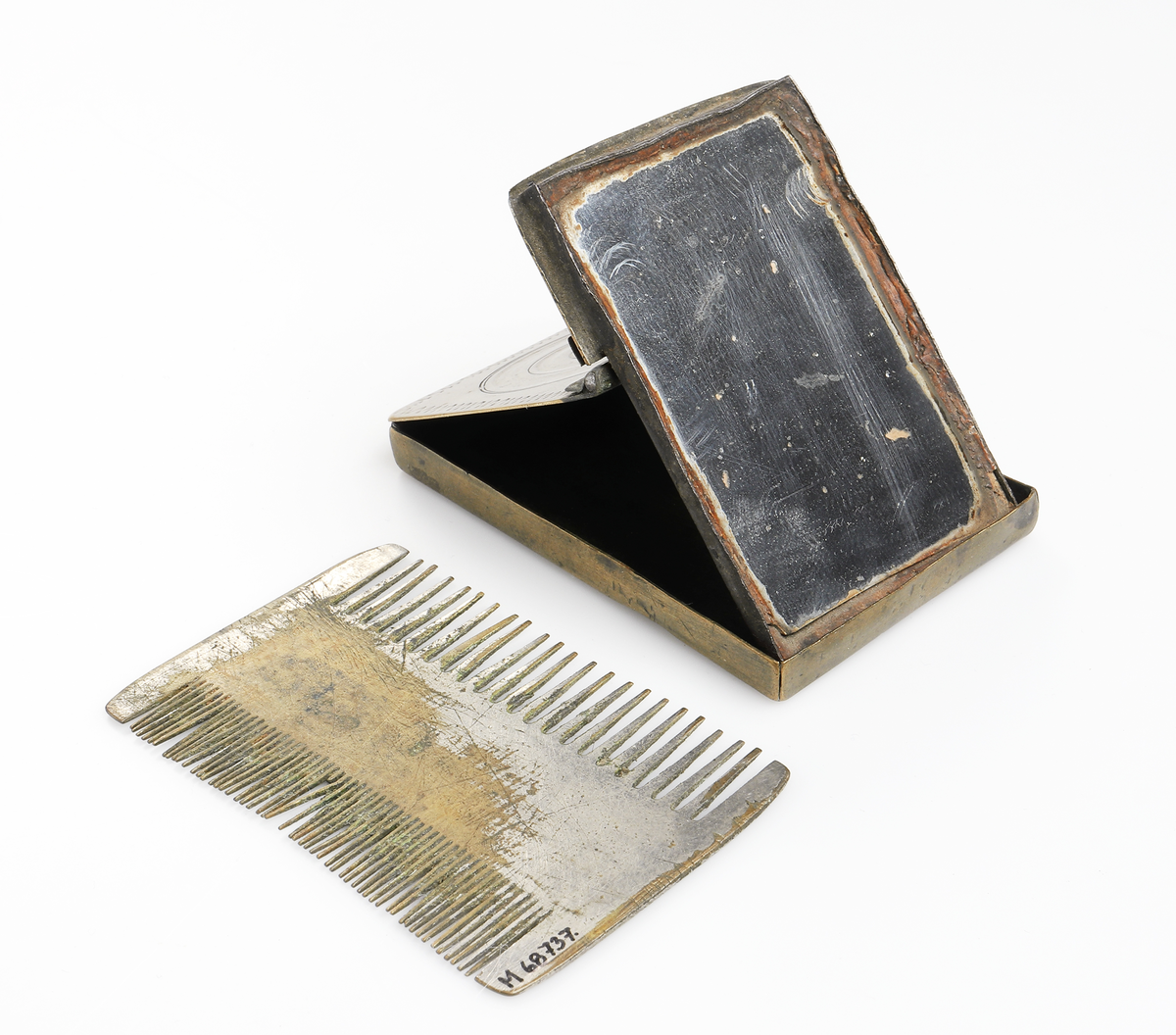 Fickspegel och tillhörande finkam i metall. I hopfällbart etui, av mässing.