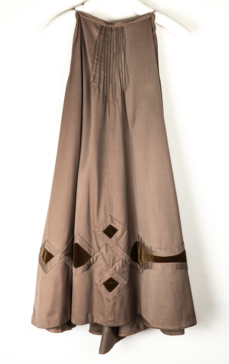 Klänning, beige yllegabardin och olivgrön sammet.
a) Kjol, klockad gabardin. Rutmönster nedtill med infällda sammetsfyrkanter. L 105cm.
b) Jacka, sammet. Krage och slag av gabardin med blommor av sammet. Knäppning fram. Långa puffärmar med slag. livet och ärmarna dekorerade med gabardinremsor. L fram 43cm, bak 37cm.
c) Väst, gabardin kantad med sammet. Urringad knäppning fram.
L fram 27cm, bak 18cm.
