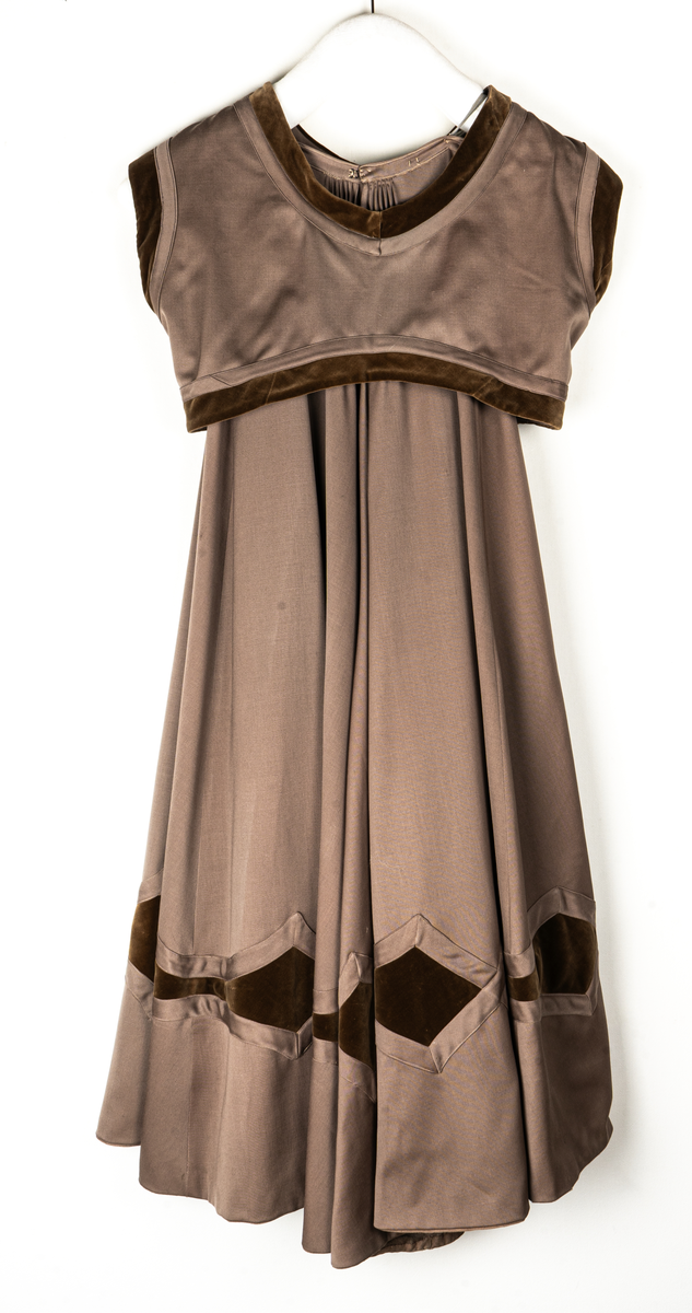 Klänning, beige yllegabardin och olivgrön sammet.
a) Kjol, klockad gabardin. Rutmönster nedtill med infällda sammetsfyrkanter. L 105cm.
b) Jacka, sammet. Krage och slag av gabardin med blommor av sammet. Knäppning fram. Långa puffärmar med slag. livet och ärmarna dekorerade med gabardinremsor. L fram 43cm, bak 37cm.
c) Väst, gabardin kantad med sammet. Urringad knäppning fram.
L fram 27cm, bak 18cm.