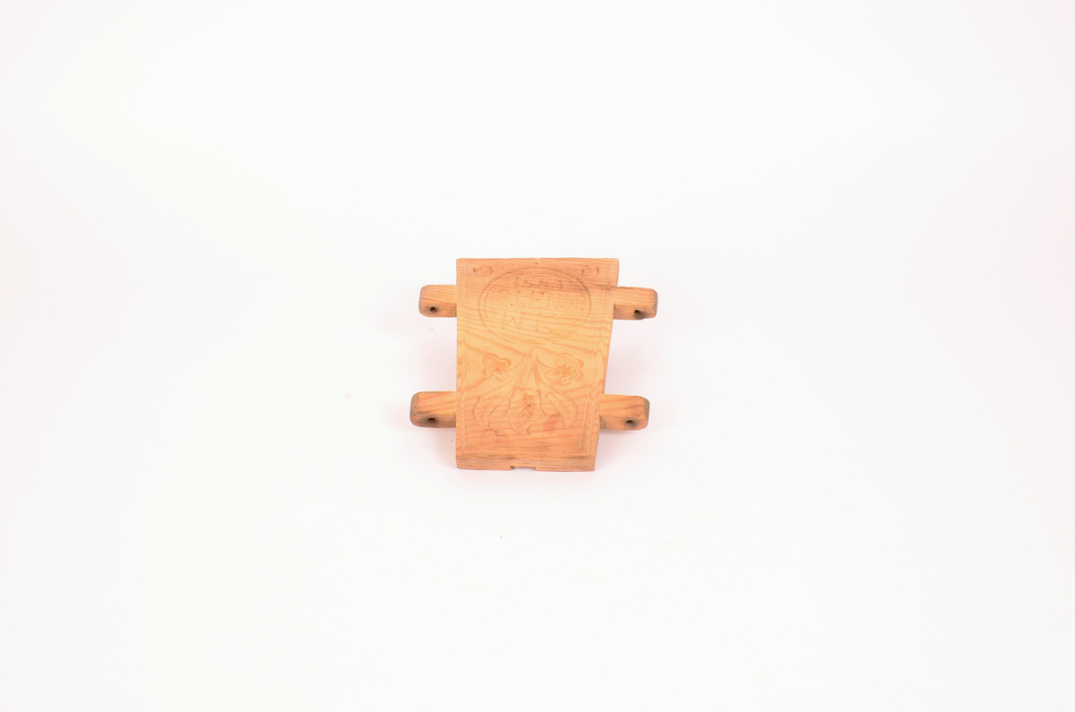 Gran, skåret. Fire sider, hver side trapesformet, skåret i et stykke og avstivet med stående labanker. To av sidene er skåret med to tapper på hver side med hull i. På de to andre, er skåret fire rektangulære hull (spalter), et i nærheten av hvert hjørne, som tappene passer inn i. Tappene settes inn i spaltene, og holdes på plass med sprosser. Sprossene mangler. I øvre kant på en av sidene er det kilt inn tilsammen tre tapper til feste for formens lokk ("tak"?). En tapp og lokket mangler. Skåret dekor på hver side.