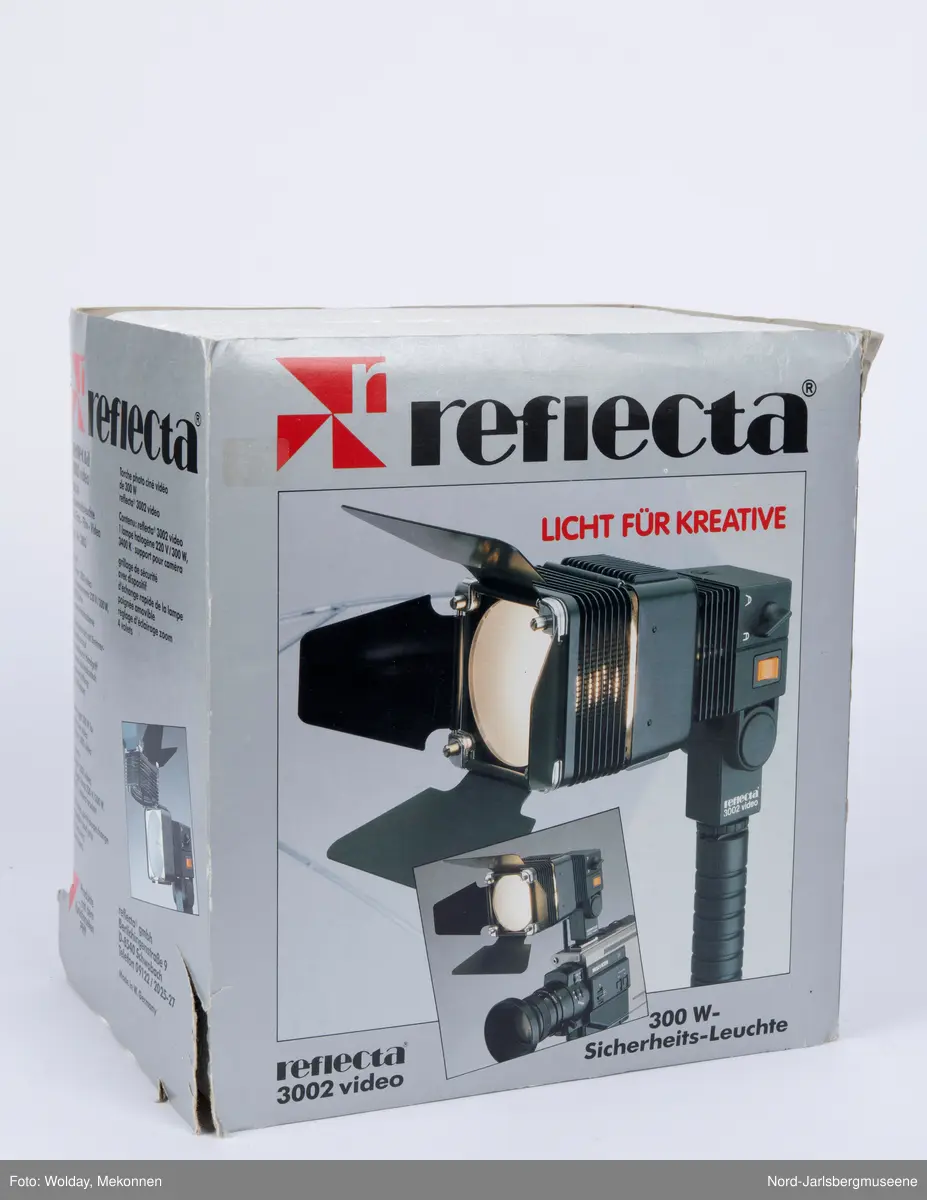 Videolys i original emballasje; isoporboks med pappomslag. Videolampen er i sort metall ledning, . Eske med ekstra halogenpærer medfølger (tom). Pappomslaget med foto av lampen invendig, med teknisk info.
Manual med veiledning på fire språk.