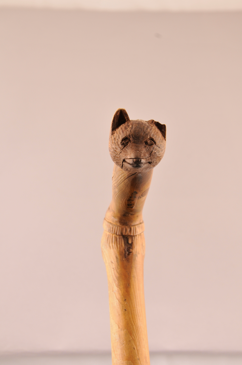 Spaserstokk med utskore ansikt og bjørnemaske på handtaket.
