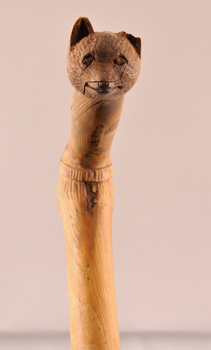 Spaserstokk med utskore ansikt og bjørnemaske på handtaket.