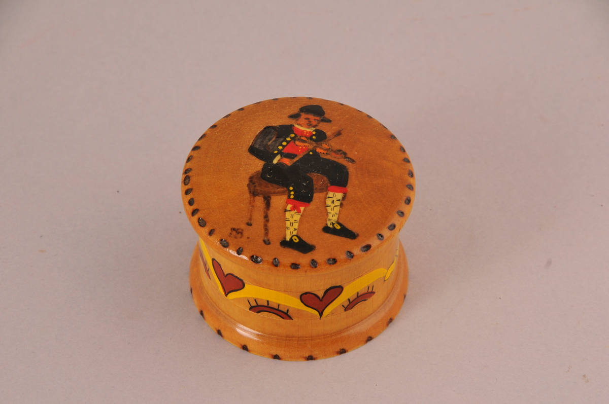 Dreia boks med lok, dekorera med sittende spilemann på loket og roser på sarg.