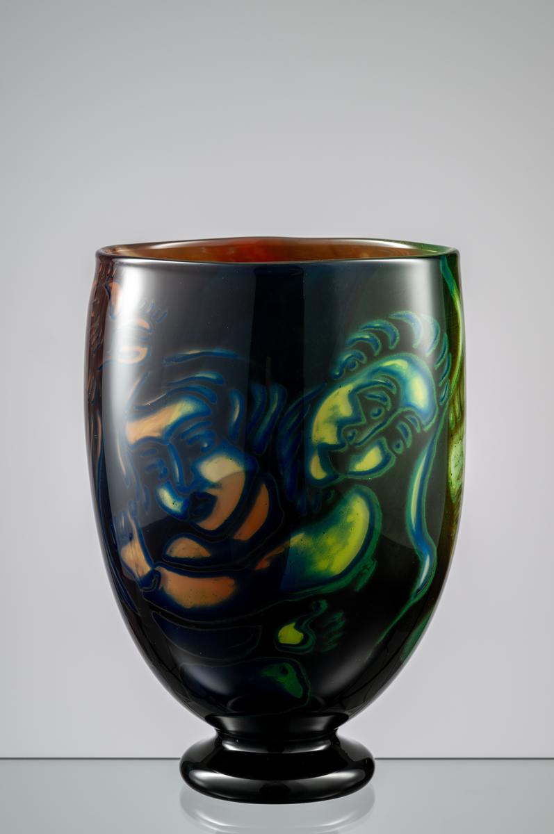 Formgivare: Eva Englund. Graalvas, ovoid form med svart låg fot. Figurmotiv med flertal ansikten i beige, grön och blekrosa nyans mot mörk fond.