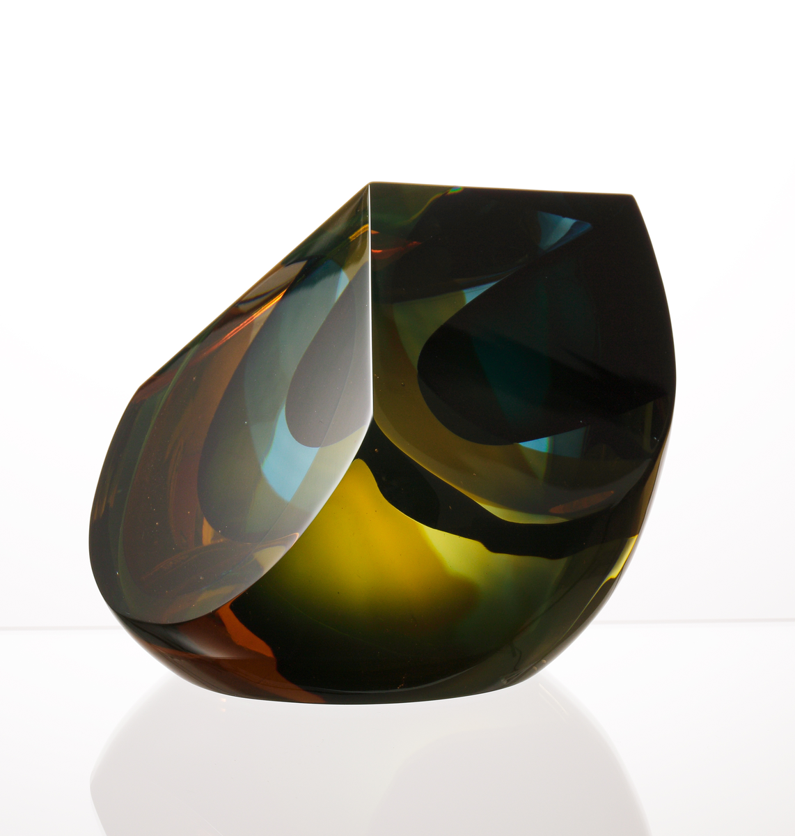 Formgivare: Eva Englund. Skulptur, liggande droppform med tre slipade väggar. Mellanfång i grön, blå och gul nyans.