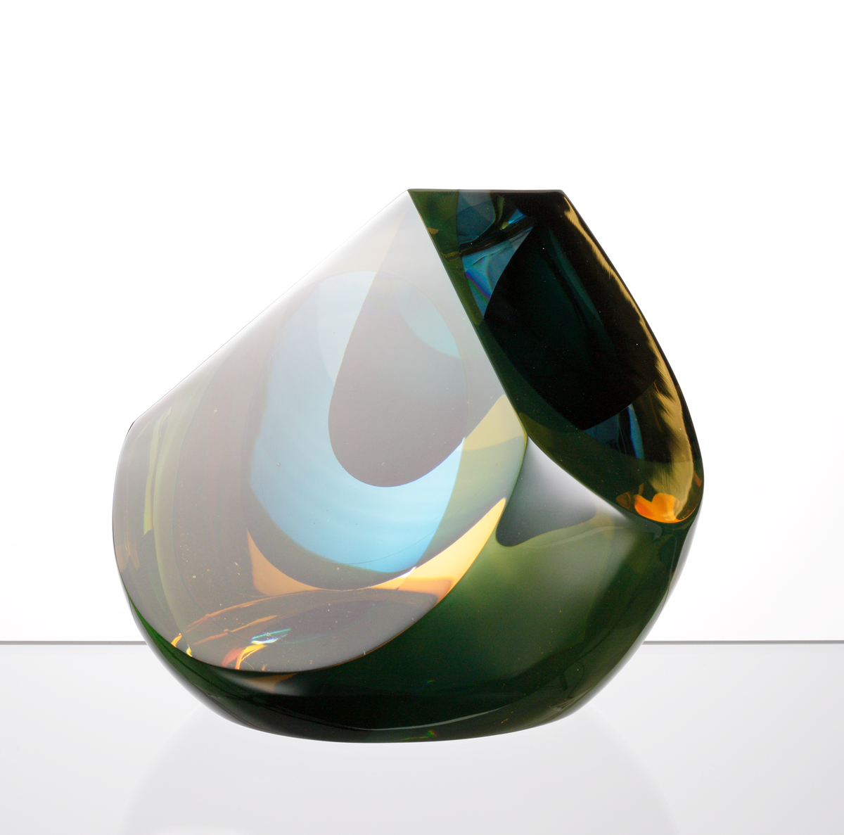 Formgivare: Eva Englund. Skulptur, liggande droppform med tre slipade väggar. Mellanfång i grön, blå och gul nyans.