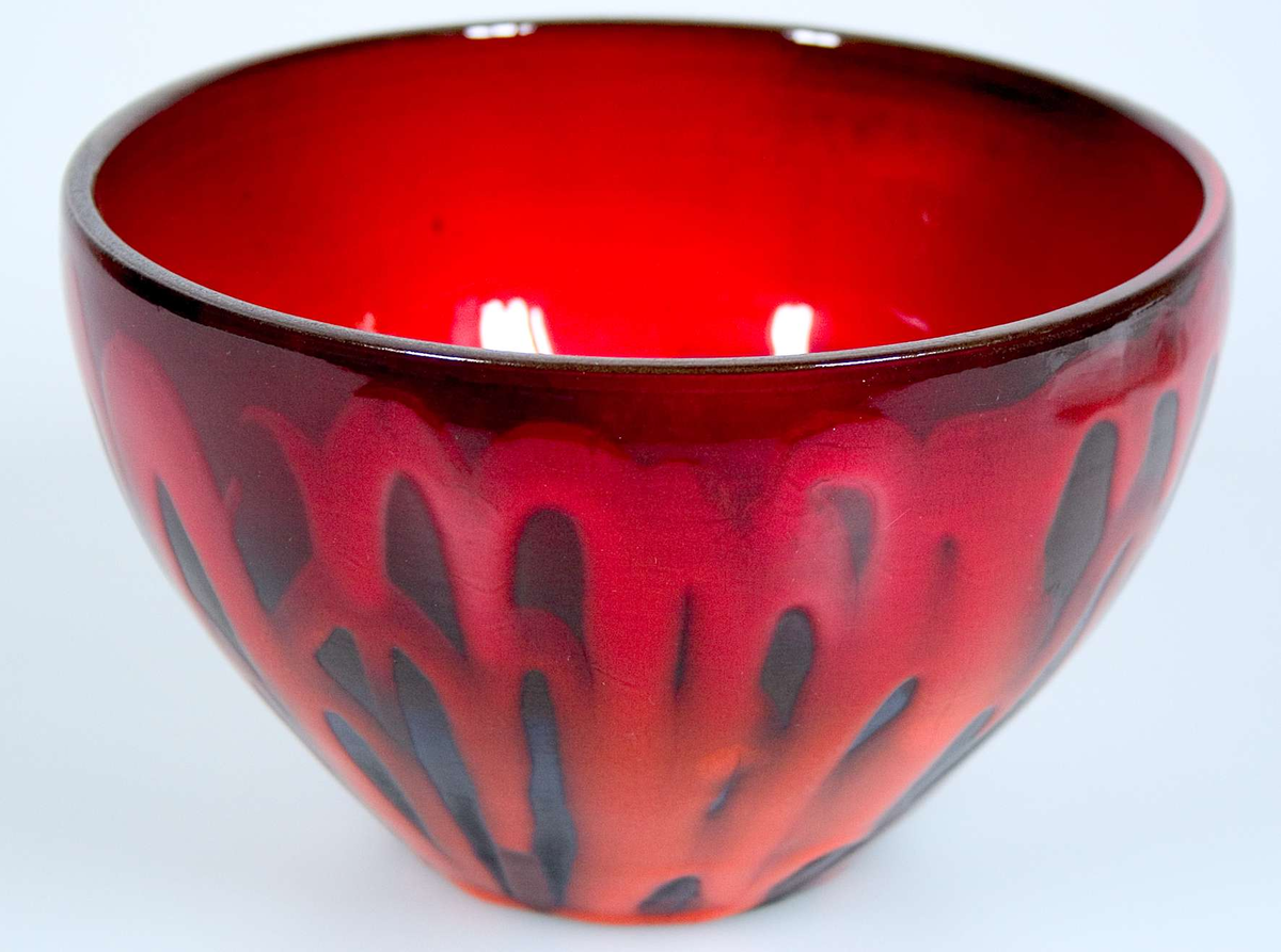 Av lergods mörkgrå med röd orange glasyr. Signerad i massan Abg.