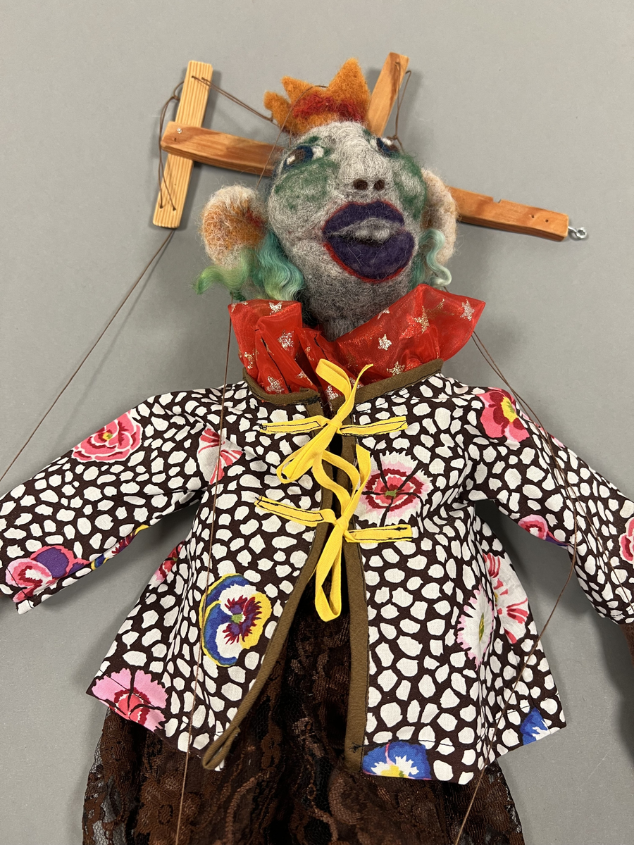 Marionettdockan är tillverkad av material som blivit över från andra projekt, ull (tovad), broderigarn, tygbitar, trä från tillverkarens trädgård. Det mesta handgjort, (tovat, sytt, broderat, skruvat och borrat.