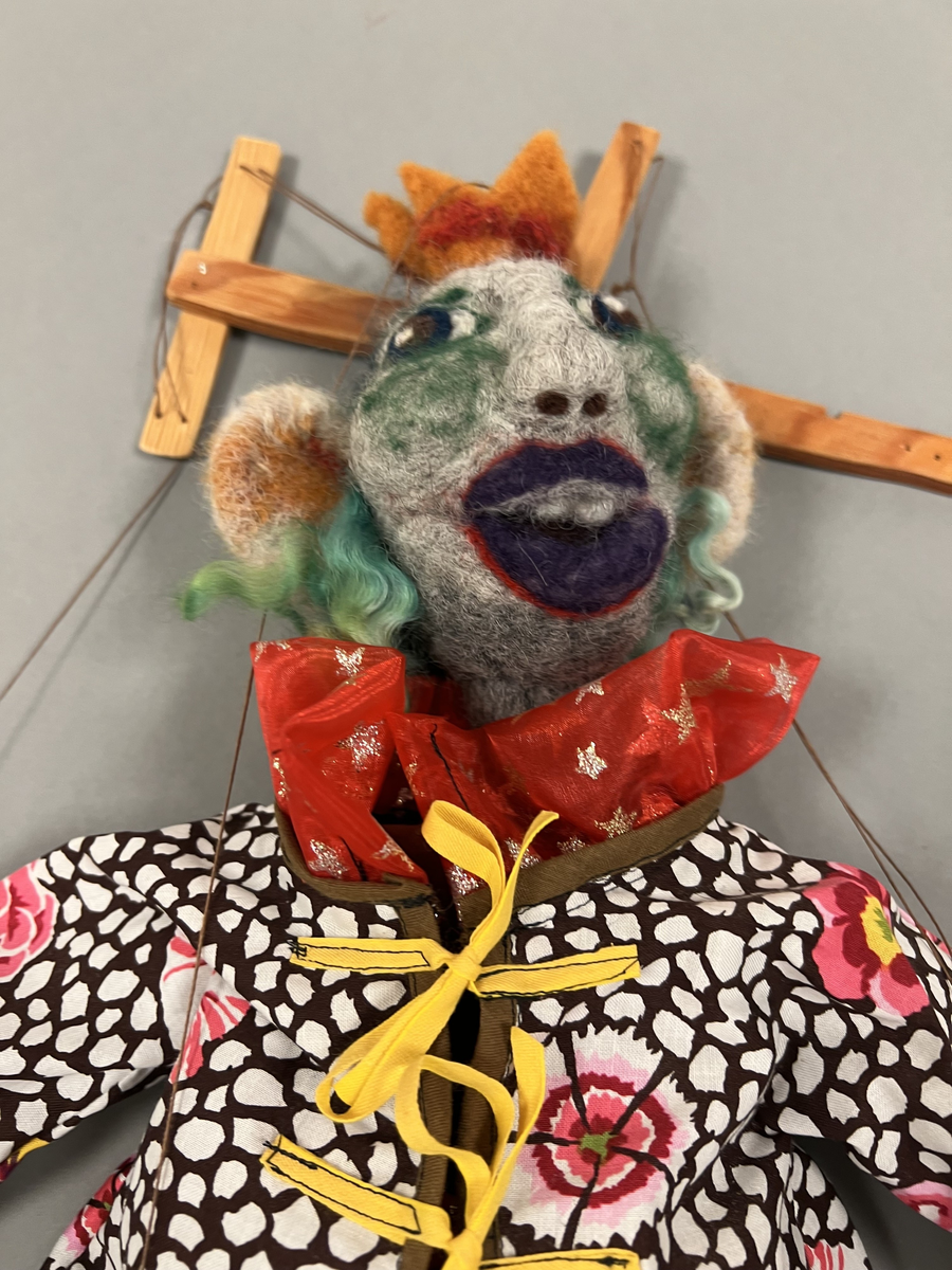 Marionettdockan är tillverkad av material som blivit över från andra projekt, ull (tovad), broderigarn, tygbitar, trä från tillverkarens trädgård. Det mesta handgjort, (tovat, sytt, broderat, skruvat och borrat.