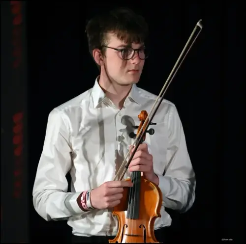 Jonathan Jansson i kvit skjorte held ei fele i eine handa og ei felebue i den andre