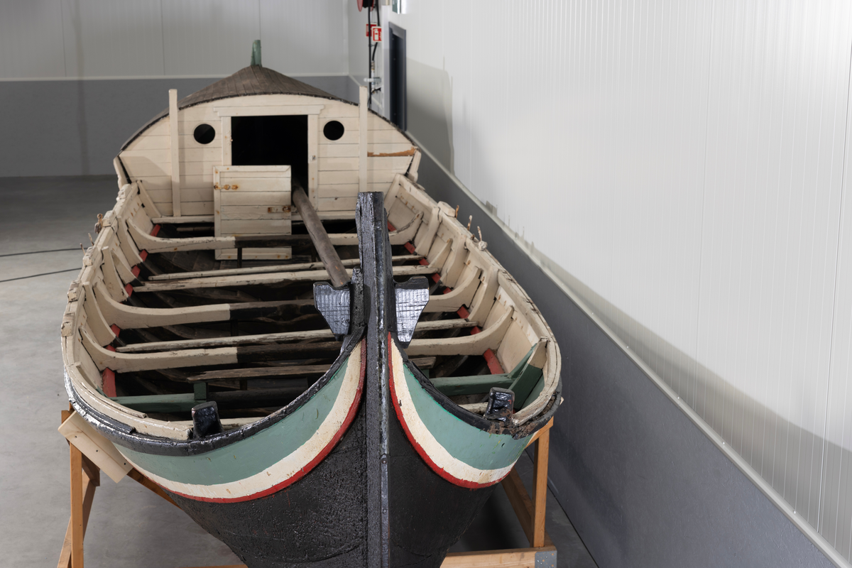 Åttring med løfting. Rødbrunt bunnstoff og tjæret skrog. Øverste bordgang har bredere grønt felt og smalere hvitt og rødt felt.