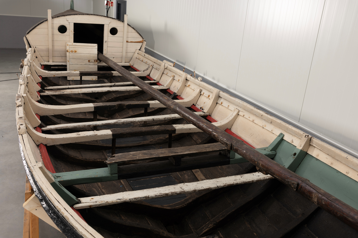 Åttring med løfting. Rødbrunt bunnstoff og tjæret skrog. Øverste bordgang har bredere grønt felt og smalere hvitt og rødt felt.