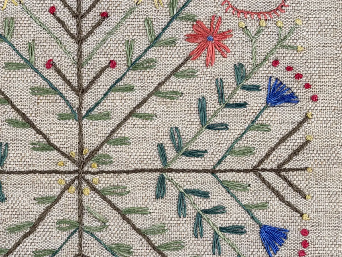 Löpare gjord av halvlinneväv i sålldräll och broderi utfört med lingarn i stjälksöm, läggsöm, langettsöm, oliksidig plattsöm, bottensöm samt knutar. 
Duken är inramad med en stjälksöm och har 7mm breda fållar runt om och raka hörn, som är sydda med kaststygn. 