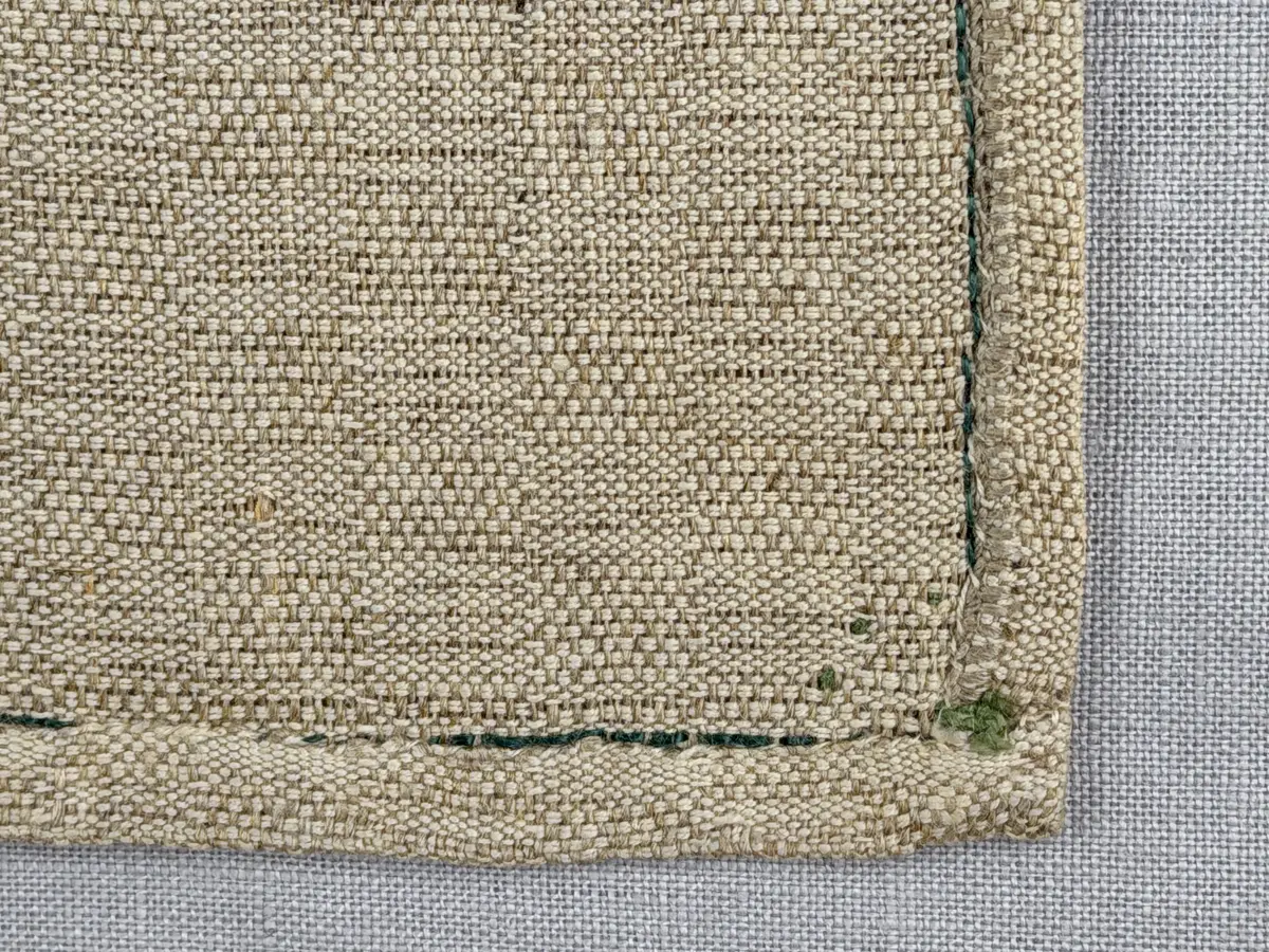 Löpare gjord av halvlinneväv i sålldräll och broderi utfört med lingarn i stjälksöm, läggsöm, langettsöm, oliksidig plattsöm, bottensöm samt knutar. 
Duken är inramad med en stjälksöm och har 7mm breda fållar runt om och raka hörn, som är sydda med kaststygn. 