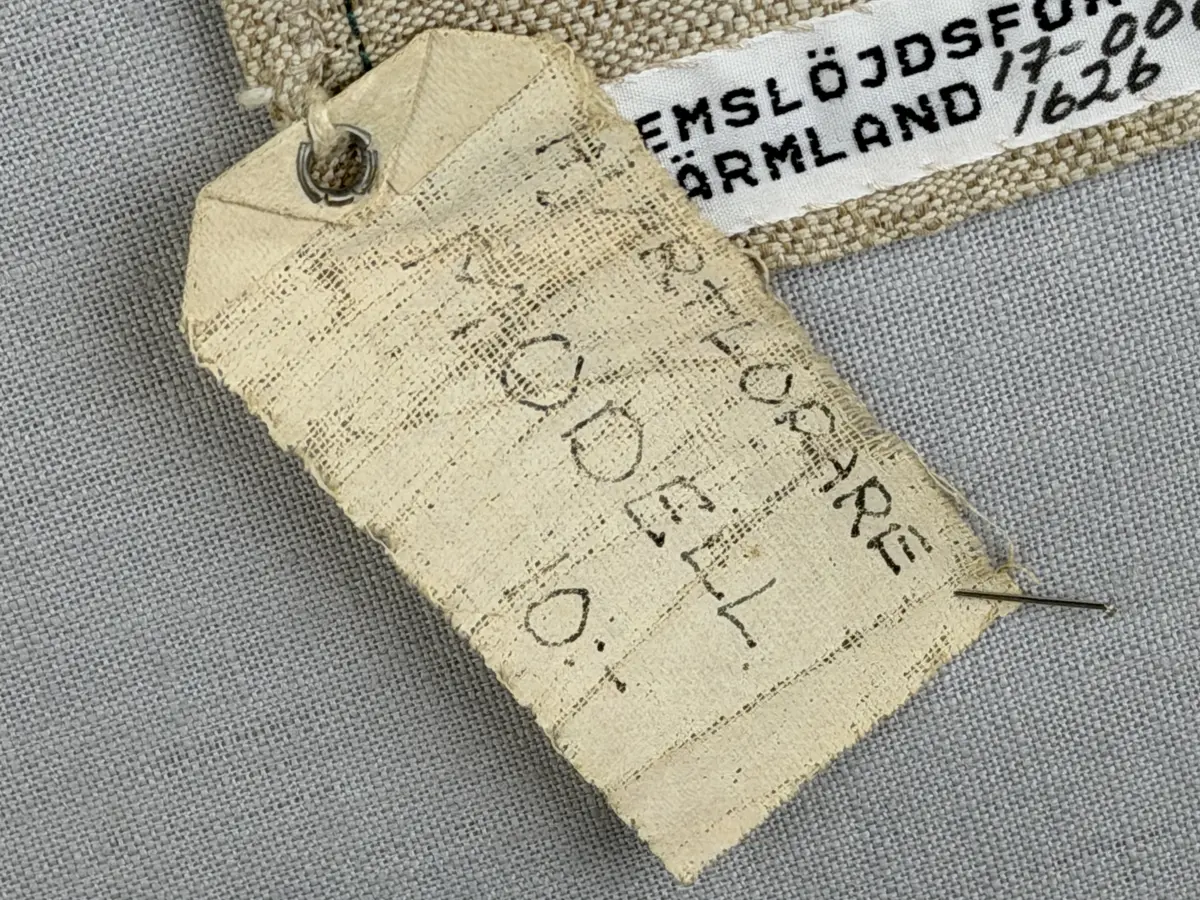 Löpare gjord av halvlinneväv i sålldräll och broderi utfört med lingarn i stjälksöm, läggsöm, langettsöm, oliksidig plattsöm, bottensöm samt knutar. 
Duken är inramad med en stjälksöm och har 7mm breda fållar runt om och raka hörn, som är sydda med kaststygn. 