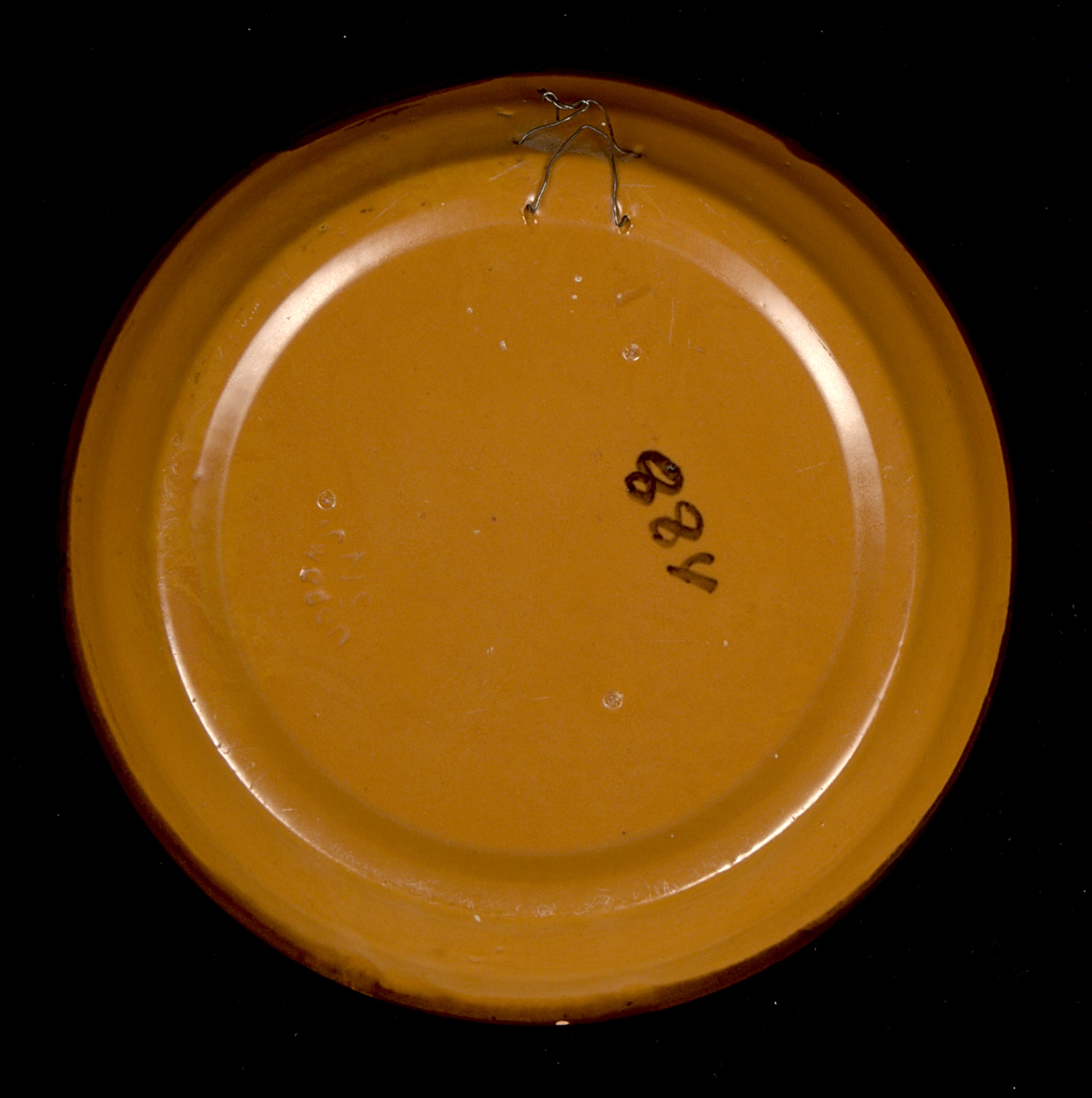 Prydnadsfat av lergods med motiv i brunt och grönt på cremevit botten. Centralt i motivet är Karl XII:s stall på Varbergs fästning. Text under motivet: "Varberg". På undersidan av fatet finns en upphöjd fotring försedd med två hål samt metalltråd för väggupphängning. Även en märkning i tusch: "884".