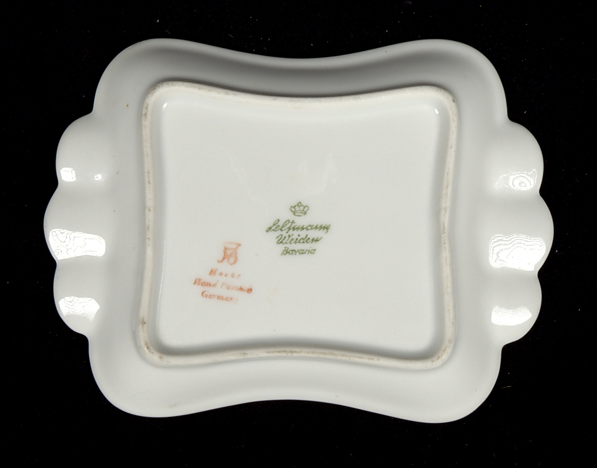 Askfat i porslin. Rektangulär form med svängda långsidor och tre guldglaserade urtag vid vardera kortsida, för placering av rökverk. I fatets mitt ett tryckt färgmotiv föreställande Varbergs fästning samt texten: "Varbergs fästning, Varberg".

På fatets undersida finns två stämplar: "Seltmann Weiden Bavaria" (grönt) och (?) "Hand painted Germany".