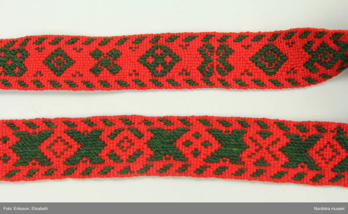 Huvudliggaren:
"Kvinnodräkt fr. Delsbo sn, Norra Helsinglands fgd, Helsingland.
a. "Ryntjeskjortel" af svart kläde med röd kant och bandväfd "kval" (linning). Kjolen "lurad"(goffrerad), skall förvaras lurad att ej vecken gå ut. 3 par fruntimmershänder hjälpas åt att "lura" den efter hvarje begagnande.
b. livstycke, rött med gröna ränder.
c. "Ryntjessärk" (rynksärk) af hvitt bomullstyg med "krus" (handbroderi) kring hals och händer.Begagnas sommartiden
d. "Bumsförkläde" af ylle, blårandigt med bandväf,"kval" i rödt och grönt.
e. "Förklesband" rödt och grönt ylle med "doppar" (tofsar) i ändarna. Lindas 1 à 2 hvarf kring lifvet och bindes framtill med stora nedhängande "locor" och ändar. Längd 262 cm, bredd 3,4 cm.
f. Kjolsäck med mässingslås och hake samt tennbroderi. Häktas under förklesbandet och hänger delvis under "försklet". Begagnas vanligen till förvaring af kyrkkryddor m.fl. kyrk-ellerkalassaker.
g. Halfhandskar af svart kläde med silkesbroderi. Begagnas sommartiden.
h. "Påshufva" hvardagsmössa af brokigt kattun. Begagnas med i nacken utslaget hår med några hårtestar hängande fritt framför öronen.
Till dräkten användes röda strumpor samt låga skor med höga klackar. Äfven kan användas silfersmycken kring halsen eller å  bröstet. En á två brokiga silkesdukar brukades omkring halsen nedstoppade under lifstycket, så att kruset kring halsen  på "ryntjessärken" sammanfästadt med ett löfspänne samt en smalare kant af hvarje sidenduk, blevo synliga. Vid handlederna sammanfästes ryntjessärken med röda sidenband eller länkknappar.

a. KJOL 
längd: 87 cm
midjeband bredd: 7 cm
av svart halvylle med svart linvarp och inslag av svart 1-tr. ullgarn, de 2 yttersta stadtrådarna är av oblekt lingarn. 4 goffrerade våder samt en slät framvåd som skarvats under förklädet med oblekt bomullslärft. 5 cm bred list av rött kläde i nederkanten runtom. Brett midjeband mönstervävt i rött och grönt ullgarn och vitt bomullsgarn. Knäppt vid framvådens vänstra sida med 2 hakar och hyskor av mässing.
b. LIVSTYCKE
längd: 39 cm
av halvylle i varptäckande kypert, varp av vitt lingarn, inslag av svart och grönt ullgarn med flaminslag av vitt, 2 fram-och sidstycken, 2 bakstycken avsmalnande till skörtveck med tre par tränsade förstärkningar av svart garn. I midjehöjd ett avsytt veck runtom, knäppt kant i kant med 8 par grova hakar och hyskor av mässing. Foder av ofärgad bomullslärft.
BE

c. ÖVERDEL
Längd: 39 cm. Längd: 58 cm - ärmlängd. Vidd: 56 cm - ärmvidd. Vidd: 114 cm. Höjd: 1,7 cm - kraghöjd. Material: Textil, bomull. Textil, linne - ärmlinning, krage. Bomullsgarn - broderi. Telnik: Tuskaft. Trådbundet broderi. Broderi, rätlinjig plattsöm. Handsömnad.
Överdel av tuskaftat vitt bomullstyg. Dubbelvikt bålstycke, isydda rektangulära halsspjäll. Täta breda stripade  rynkor mot halskrage i bomull, 1,7 cm hög. Kragen har broderier i rätlinjig plattsöm, vitt bomullsgarn över hela ytan, nuggor i kanten, langetterade bågar  i framkant. 16 cm långt sprund fram, tränsad förstärkning nedtill, 3 cm.  Vidsydd ärm med  infällda ärmspjäll, lagda veck över axeln fram och bak. Täta breda stripade rynkor mot 2,5 cm bred ärmlinning. Ärmlinningen har yttäckande vita broderier i rätlinjig plattsöm, rombiska former. Vita knytband i bomull i ärmlinningar och krage. Överdelen är handsydd.
/Inga-Lill Eliasson 2007-11-26


d. FÖRKLÄDE
längd=vådbredd: 82 cm
bredd: 97,5 cm
av halvylle, varp av svart lingarn, inslag i varptäckande kypert av svart 1-tr. ullgarn med smala ränder istarkt blått och en knappt synlig svart tråd med vita flamgarnsfläckar av bomull. Upptill stripade rynkor där de blå bårderna utnyttjats dekorativt i rynkningen. Mönstervävt midjeband i grönt på rött ullgarn , bandet knäpps med 2 hakar och hyskor i vänster sida.
I nederkantens båda hörn infodringar på insidan av svart bomullslärft, för att tyget inte skall rulla sig.



Berit Eldvik 2004