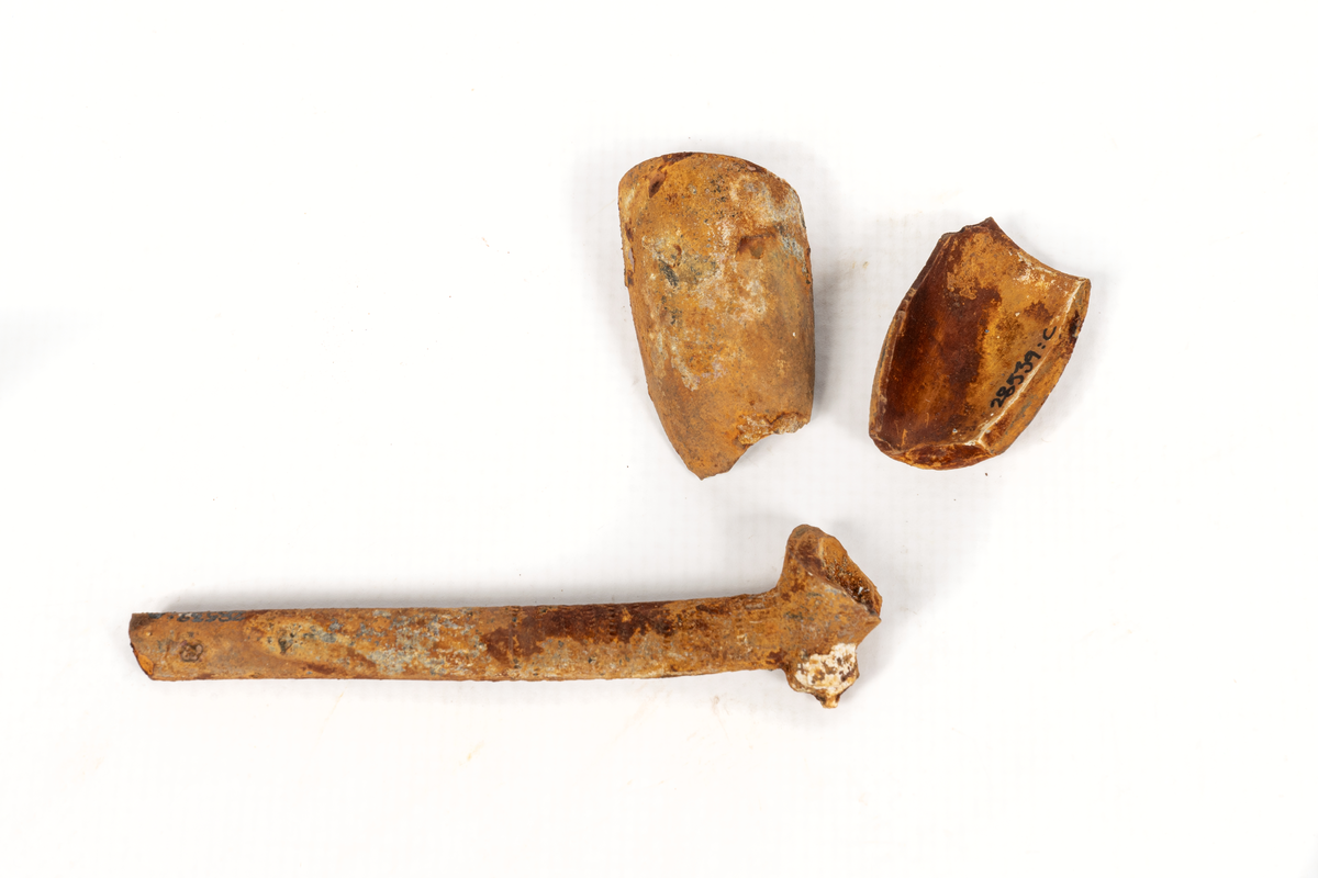 Punktornamentik i band runt skaftets nedre del samt svag punktornamentik runt  huvudets mynning. I tre delar.