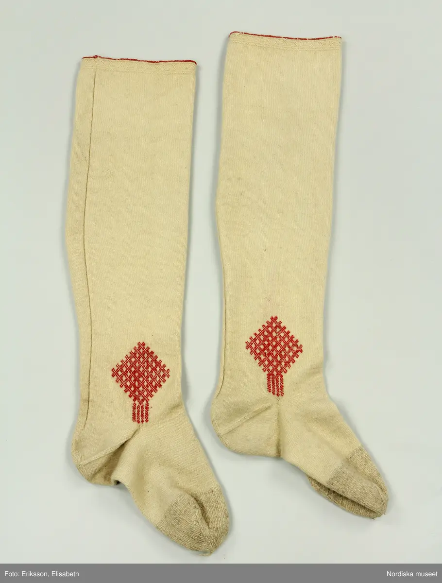 Mansdräkt i flera delar a-d.

a. Rock av svart vadmal
b. Röd väst
c:1-2 Vita strumpor
d. Knäbyxor av sämskskinn
Katalogkort finns.

a. Långrock av svart vadmal. Framstyckena/sidstyckena helskurna, ryggstycket smalt och kort,  avkuret i midjan, rikt veckat bakskört försett upptill med två ulltofsar och med pikerade klaffar en vid var  sida om skörtet. Svängda ärmar med 2 sömmar och blindslag med sprund oknäppt med 2 hakar och hyskor. Ståndkrage. Skoning av hemvävda ylleband i flera färger längs livets insidor, knäppning med hakar och hyskor.
"Dylika rockar tillhörde högtidsdräkten, vid mindre fester och till kyrkan brukades grå rockar af liknande snitt, ett snitt som gaf anledning till benämningen ´fiolen´för nysockenströjans ryggtafla ".
b. Väst av röd vadmal med ryggstycke av grovt oblekt linne i spetskypert. Hög ståndkrage och utvikta slag, med en uddklippt vadmalsremsa i kanten, dubbelknäppning med  vitmetallknappar, fästa på insidan med skinnremsa, knapphål tränsade med grönt ullgarn. 2 sidfickor med list. Foder av oblekt linnelärft, på kragens insida en bit av ryggtyget mitt bak.
c:1-2 . Strumpor slätstickade i tvåändstickning av fint vitt 1-trådigt ullgarn. Uppläggningsvarvet med rött och vitt ullgarn,  smal mönsterstickad överkant. Häl och tå av annat naturgrått garn. Mitt bak en sömmarkering med en avig maska. Vid anklarna broderade rombiska figurer i genombrutet mönster, kallas "löver" i rött ullgarn.
d. Knäbyxor av gult sämskskinn, med bred lucka med 5 knapphål, midjegjord knäppt med 2 knappar. Knapparna är av flera olika sorter av mässing, en av hängselknapparna av horn, 2 bak saknas. Midjegjorden fodrad med linnelärft. Knäsprund knäpps med 4 hakar och hyskor. Flikar vid sprunden uddklippta.
/Berit Eldvik 2010-01-08
