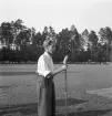 Idrottstävlingar på Värendsvallen, 1944.
En man med uppkavlade skjortärmar talar i mikrofon på plan.