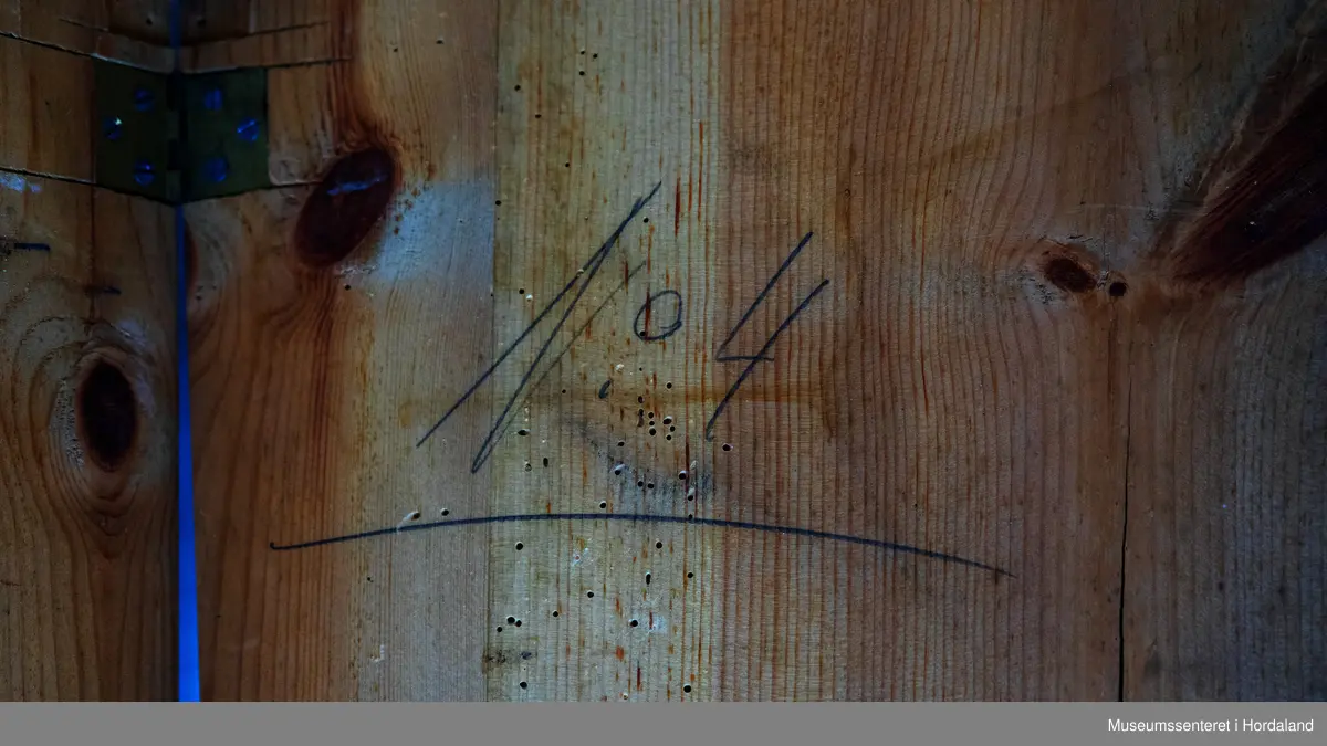 Bukseformer i tre. Kan brettes i to, Ble antakeligvis brukt til å tørke og forme ferdige underbukser før salg. Den har to hengsler.
Har to innfelte forsterkninger i tre, på tvers.