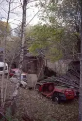 Medföljande text: "Bilvrak vid förfallen lada, vägen mot ste