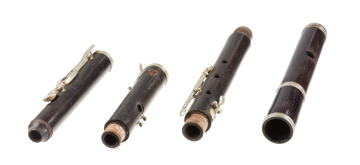 Tvärflöjt i mörkt trä med silverringar. 5 delar. Konisk form. Något krökt. Nedersta ringen saknas. 8 klaffar med kullagring och runda plattor, varav 1 klaff saknas. Sprickor i munstycke och päron. Nedre mellanstycke sprucket och amatörmässigt lagad.