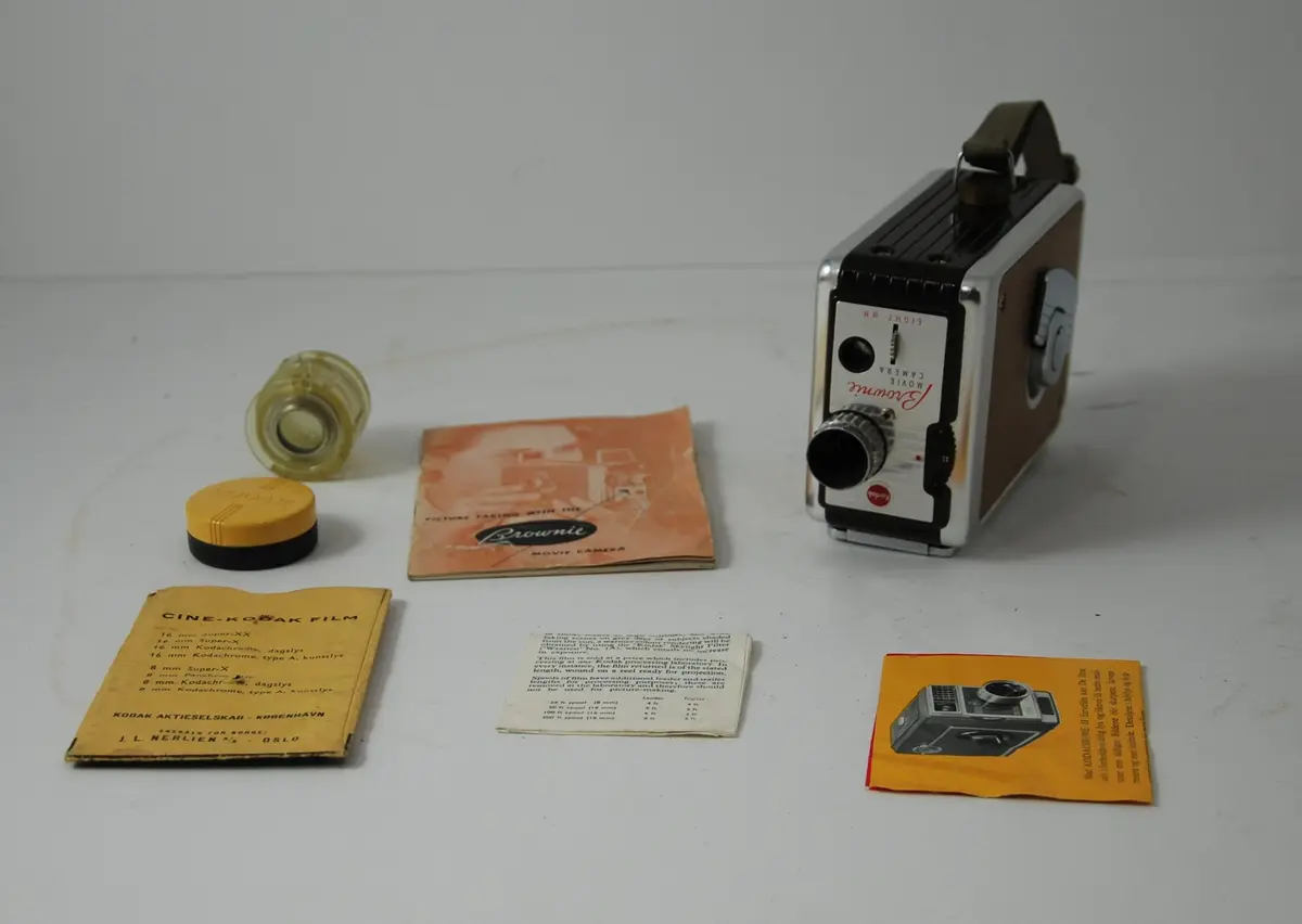 Form: rektangulær, bredere oppe enn nede, linse på kortside, sveiv for film på langside, knapper for blender etc.
