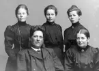 Gruppbild med familjen Fredriksson i Uppgränna. Tre döttrar står bakom sittande föräldrar. Alla kvinnor i mörka klänningar.