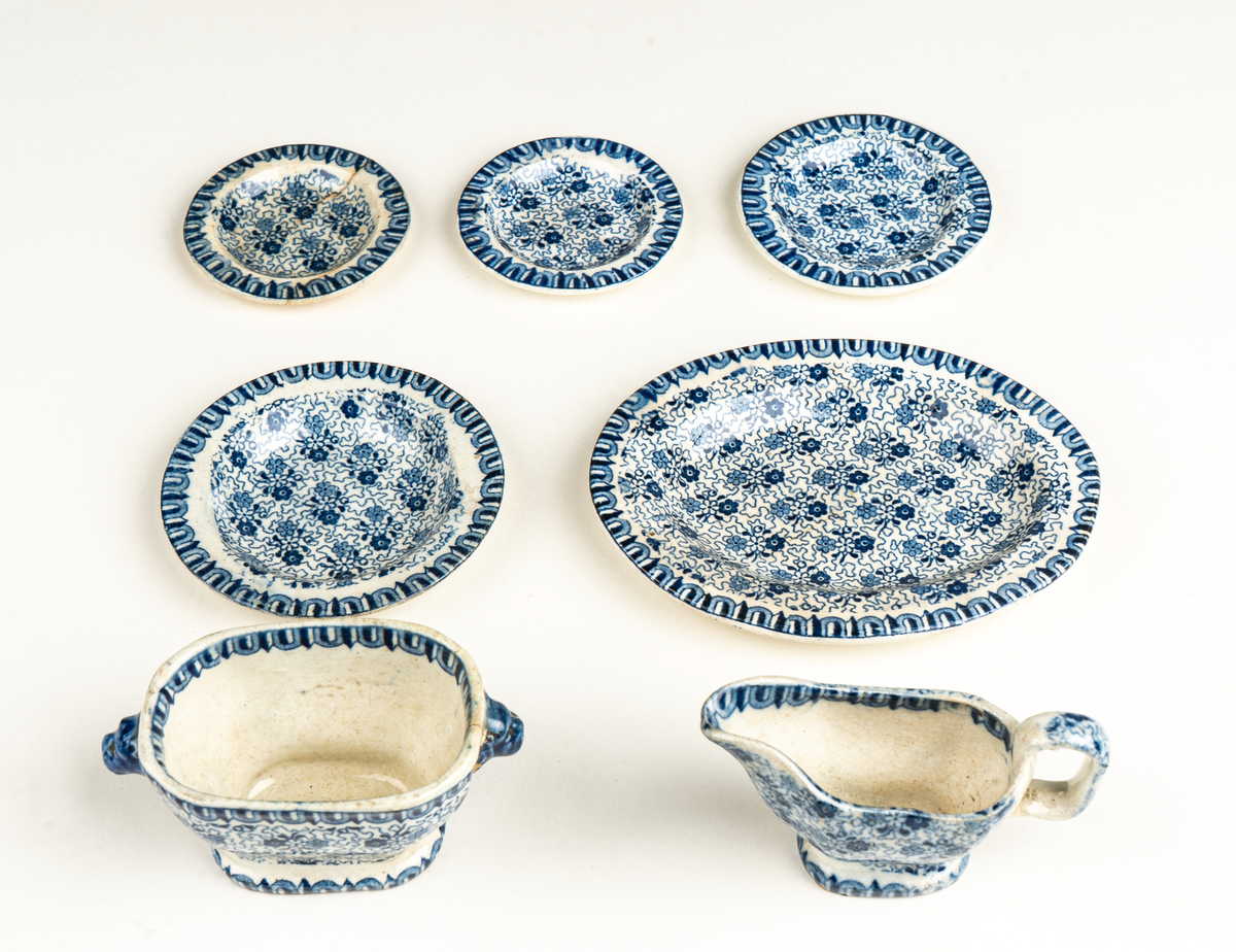 Fat, till dockservis. Ev flintgods. Glaserad. Vit med foralt mönster i blått. Ovalt. Vit och blå etikett.