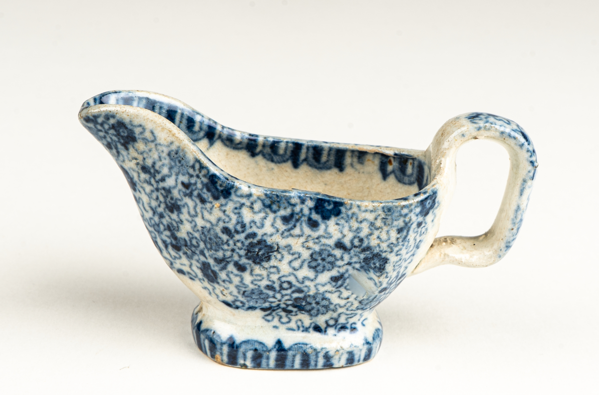 Fat, till dockservis. Ev flintgods. Glaserad. Vit med foralt mönster i blått. Ovalt. Vit och blå etikett.