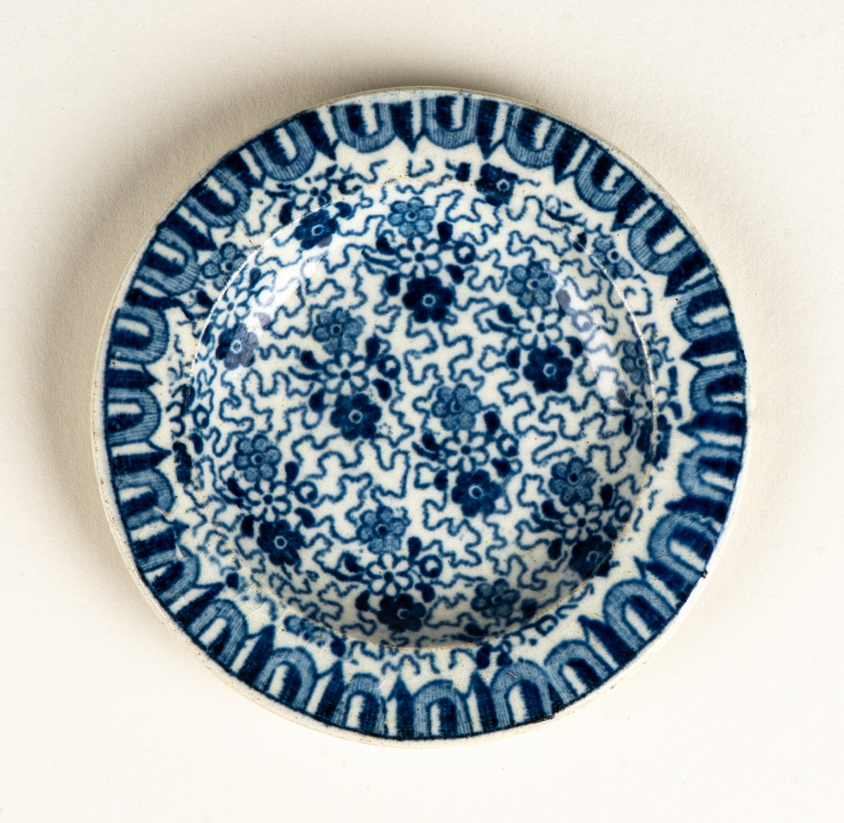 Fat, till dockservis. Ev flintgods. Glaserad. Vit med foralt mönster i blått. Ovalt. Vit och blå etikett.