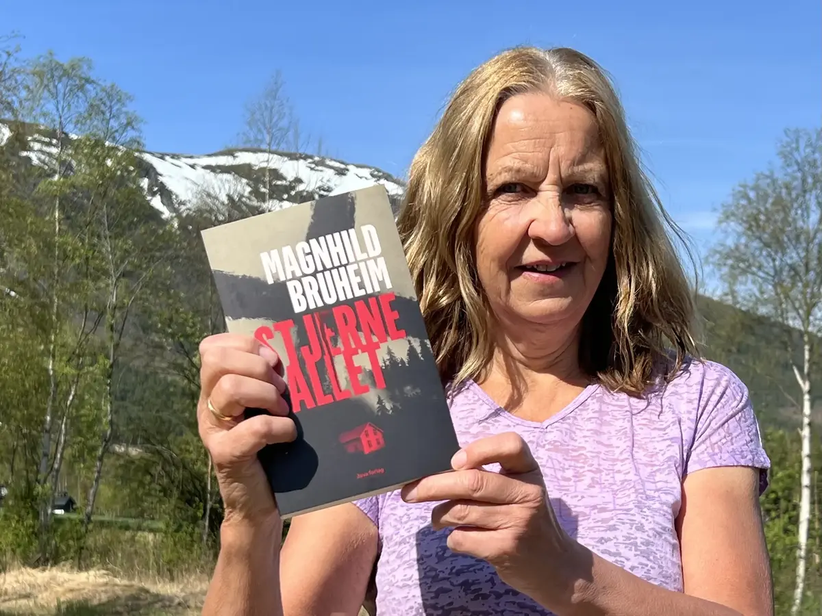 Bilete av Magnhild Bruheim med lilla tskjorte som held boka si «Stjernefallet».