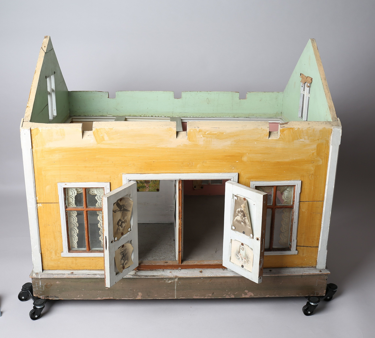 Rektangulært dukkehus i treverk med fire faste vegger. Huset består av fire rom og åpen loftsetasje. Totalt har huset ti vinduer og to doble dører som fungerer som enkeltdører. Utvendig er huset malt gult med hvite lister og brune dører og sprosser. Innvendig er gulvene malt grå, veggene rosa og gule med hvite innvendige sprosser. Gardiner i hvitt blondepapir og papirbilder er festet på veggene med tegnestifter. Veggene på loftet er malt mintgrønn.