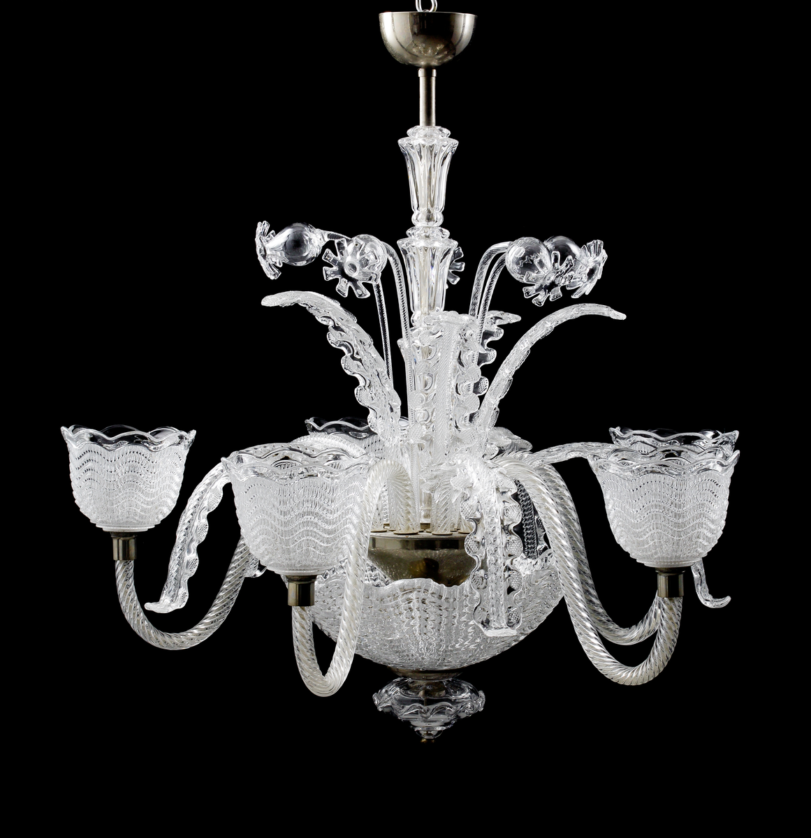 Takarmatur formgiven av Fritz Kurz. Underst en skål i pressat glas vari en infästningsanordning döljer sig. I denna sitter fem s-formade ljusarmar för elektriskt ljus placerade, tillsammans med sammanlagt tio stiliserade växt-dekorationer.