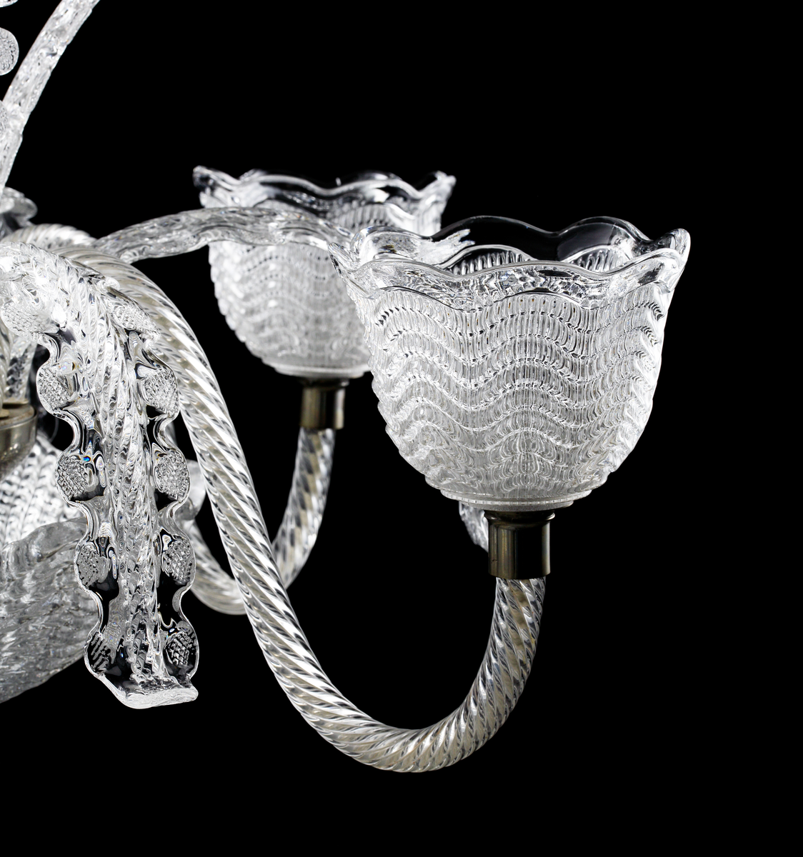 Takarmatur formgiven av Fritz Kurz. Underst en skål i pressat glas vari en infästningsanordning döljer sig. I denna sitter fem s-formade ljusarmar för elektriskt ljus placerade, tillsammans med sammanlagt tio stiliserade växt-dekorationer.